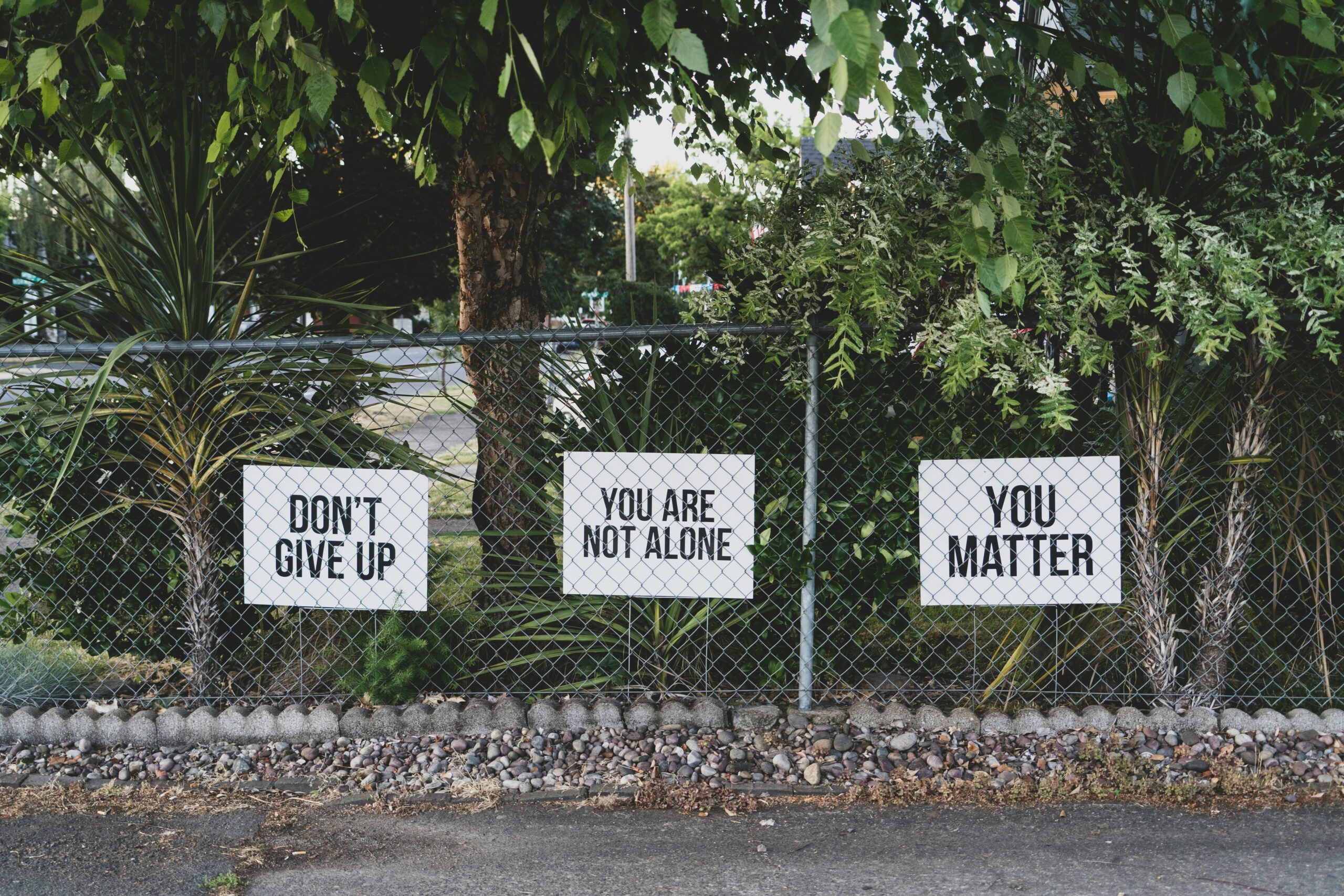 Fence with signs that say positive messages, representing mental health services for the masses through community outreach