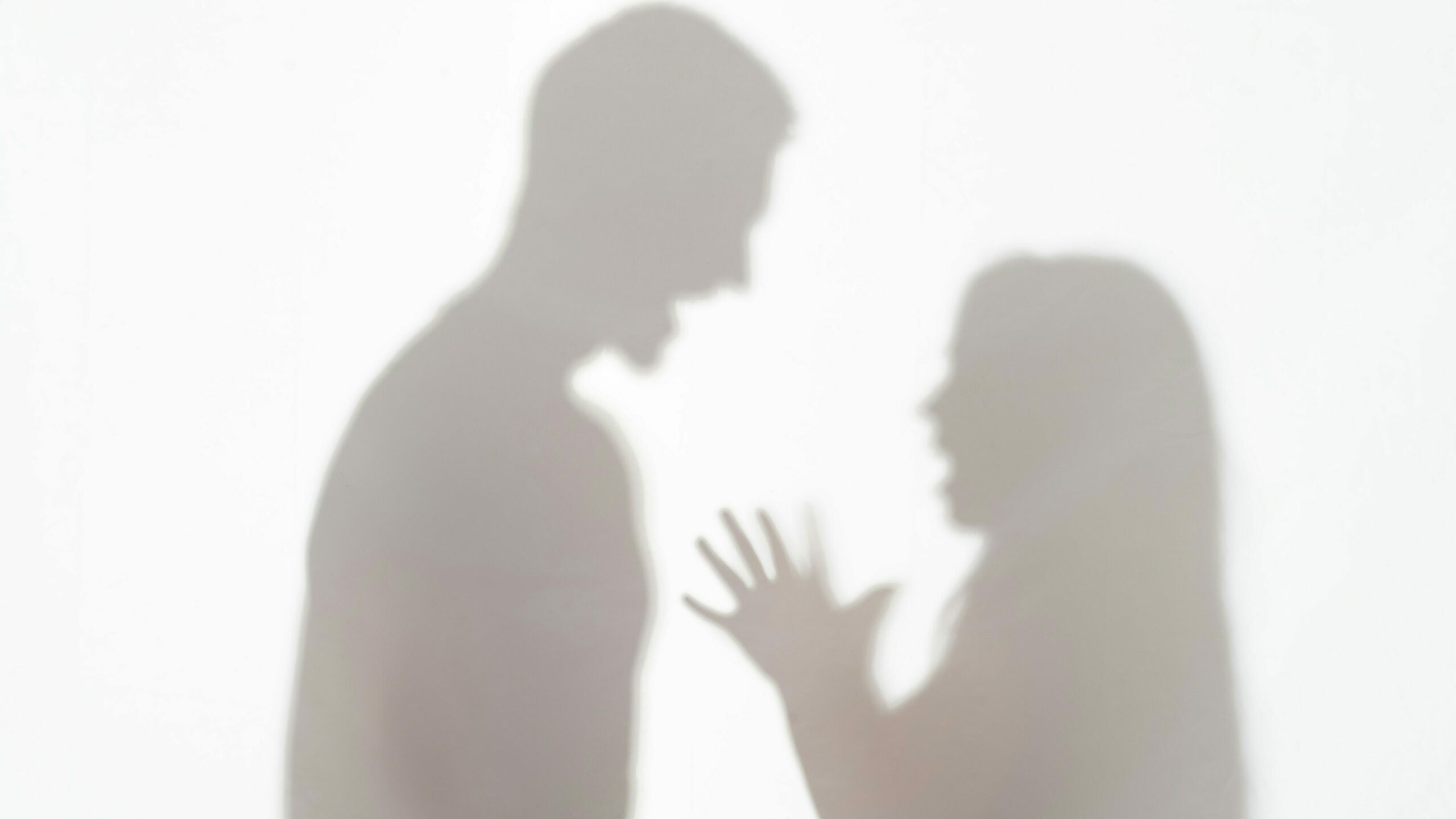 Silhouette of a couple arguing, with one person raising their hands in distress. This image underscores the need for domestic violence services to support individuals in abusive relationships.