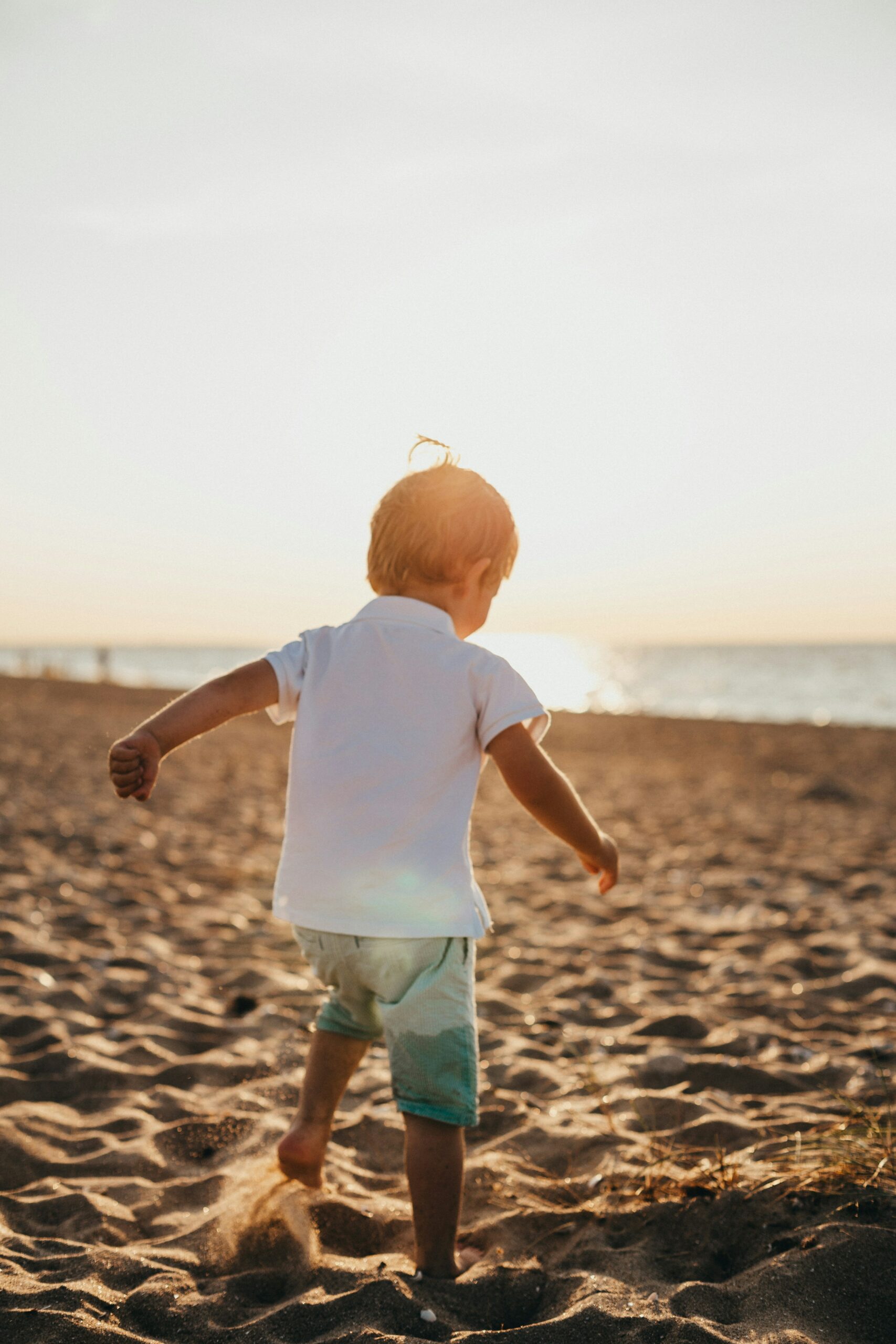 Young child playing on a sandy beach at sunset, symbolizing the nurturing and supportive environments provided by Children's Home and Community-Based Services (HCBS) for early intervention and developmental support